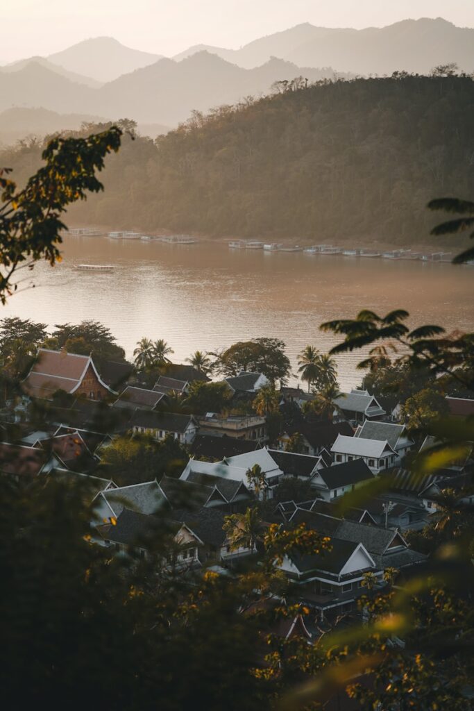 Village nestled by a wide river with mountains beyond